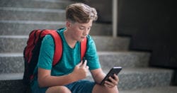 A school kid holding his phone and vaping