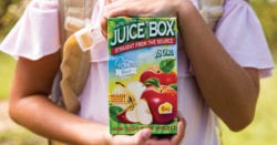 A child holding a big box of vape juice that looks like apple juice