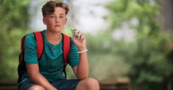 A teen boy holding a vape pen