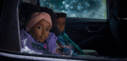 Two children riding in the back of the car