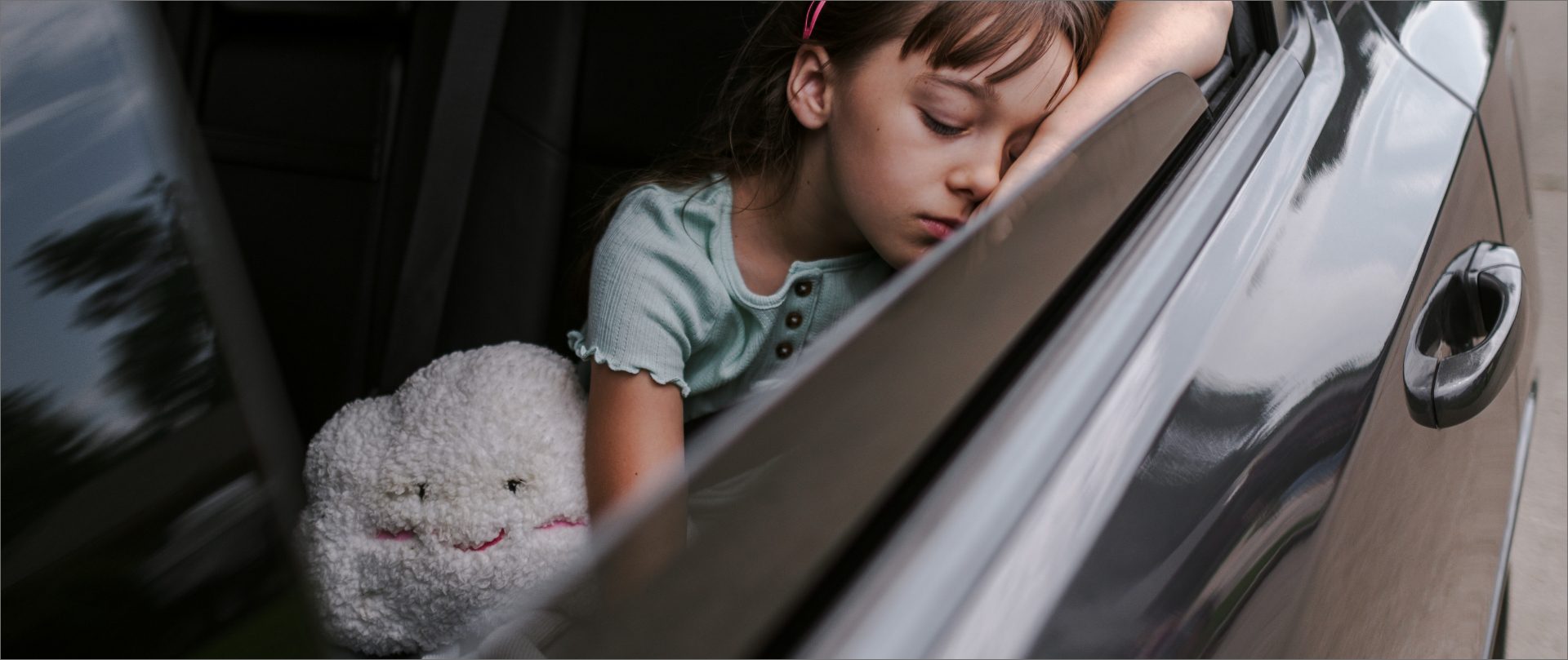 girl sleeping in the car with a cloud plush