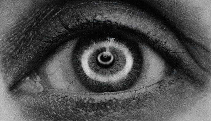 Up close photo of eye in black and white with smoke rings reflected in it