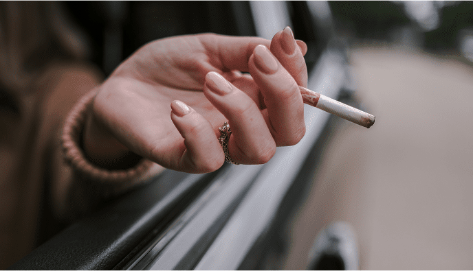 Woman holding cigarette outside car window