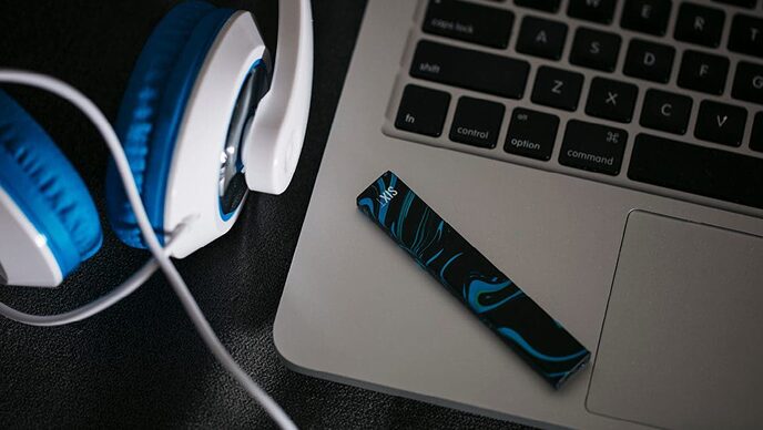 Vape on laptop next to headphones